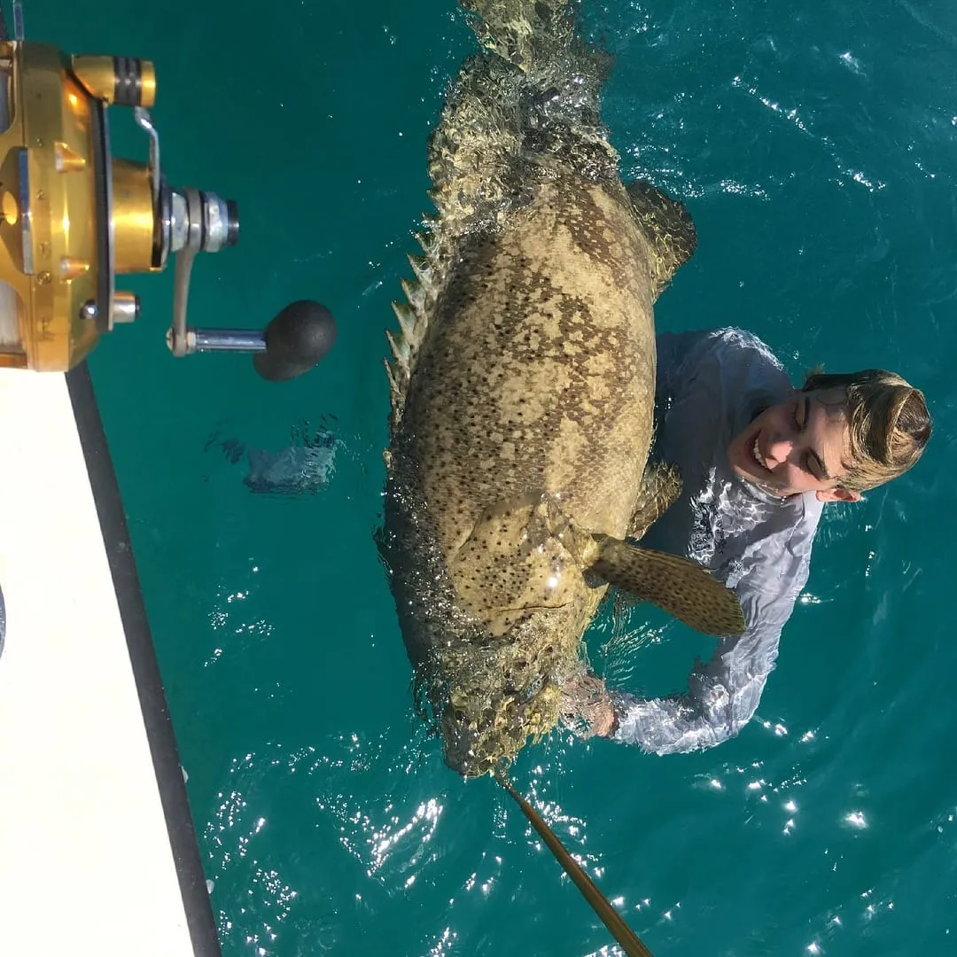 Angler holding a big grouper over the water