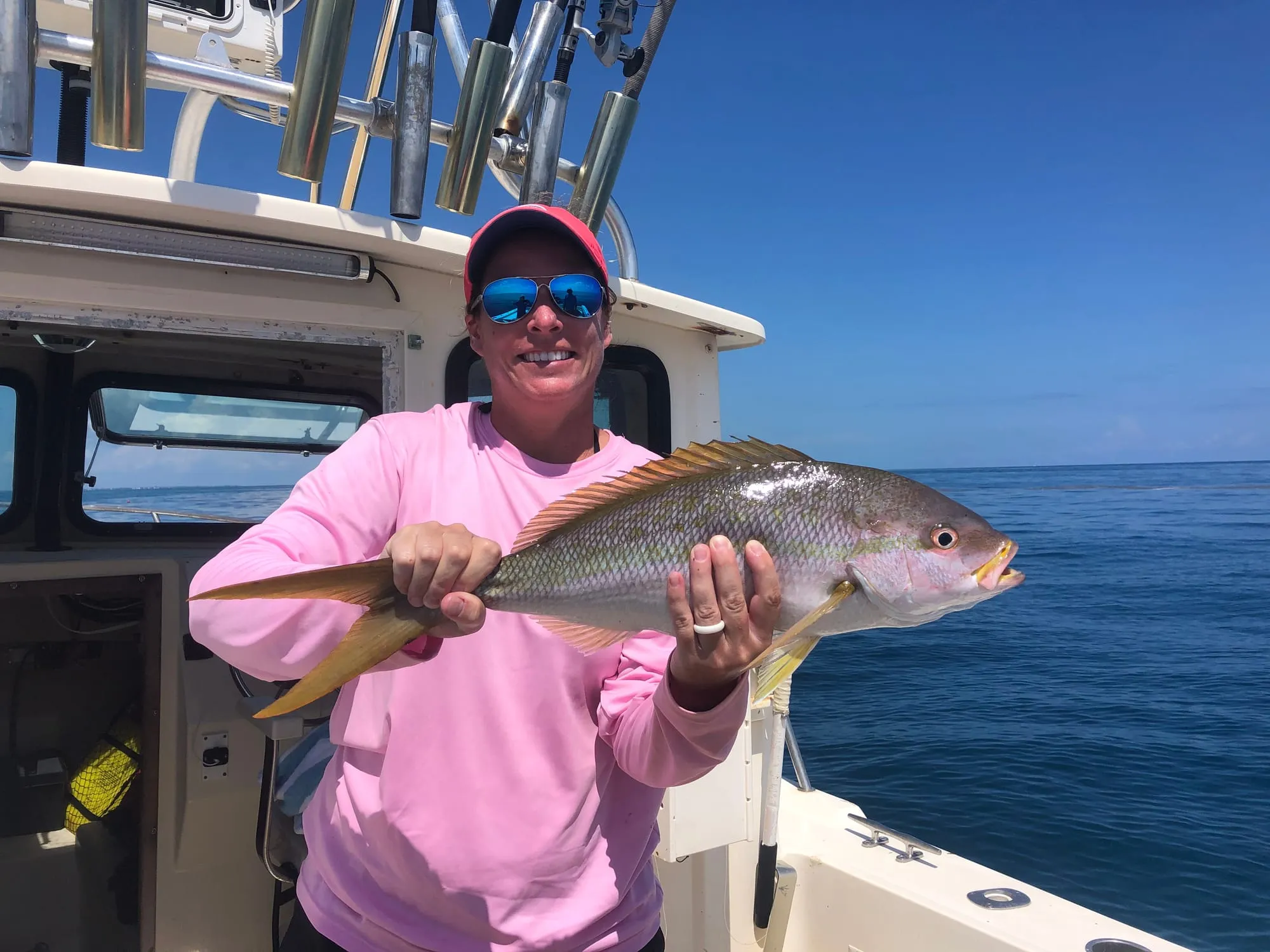 Angler holding a yellowtail snapper on the open deck of Satisfaction