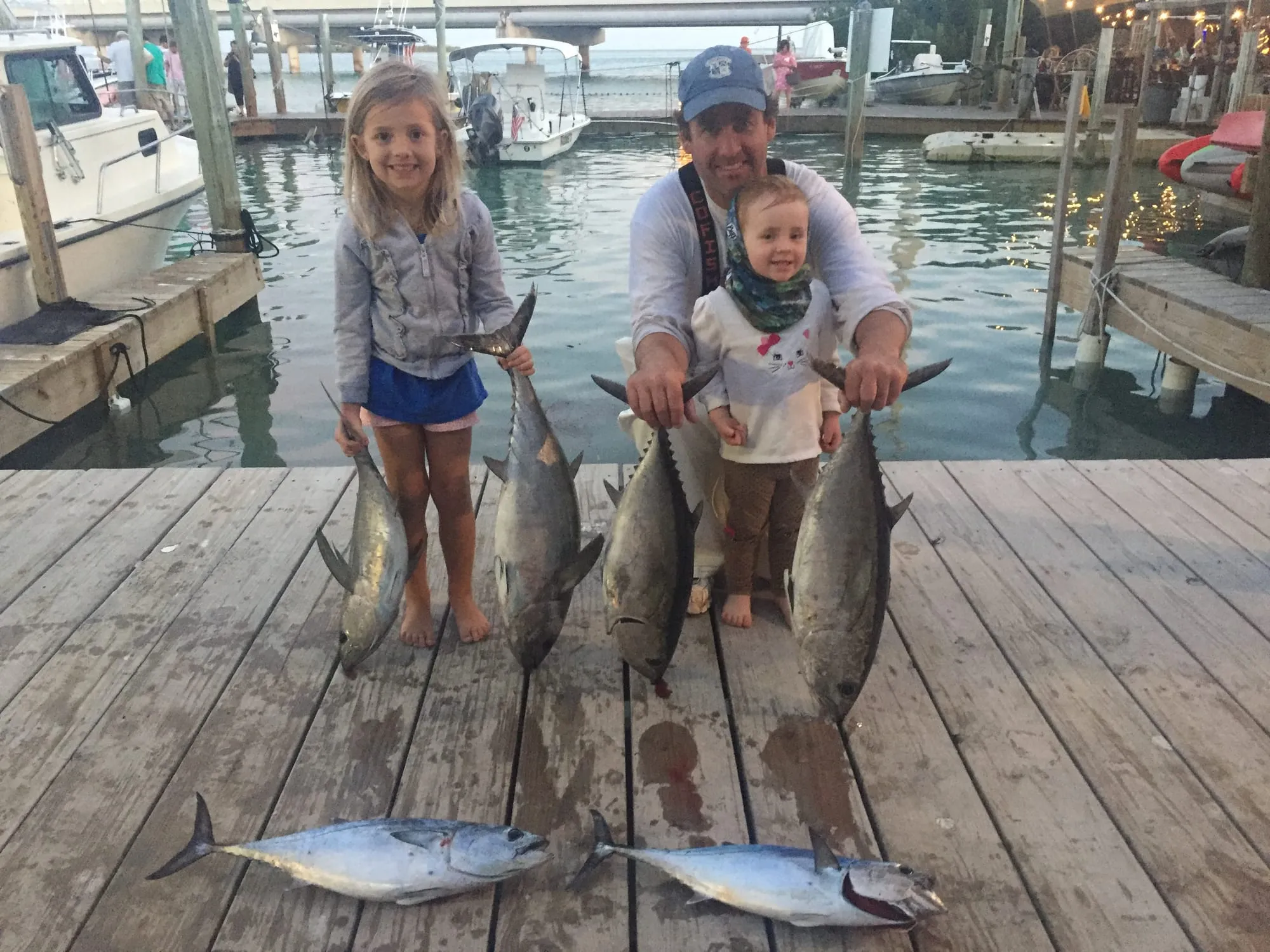 Two kids on the dock with a row of blackfin tuna