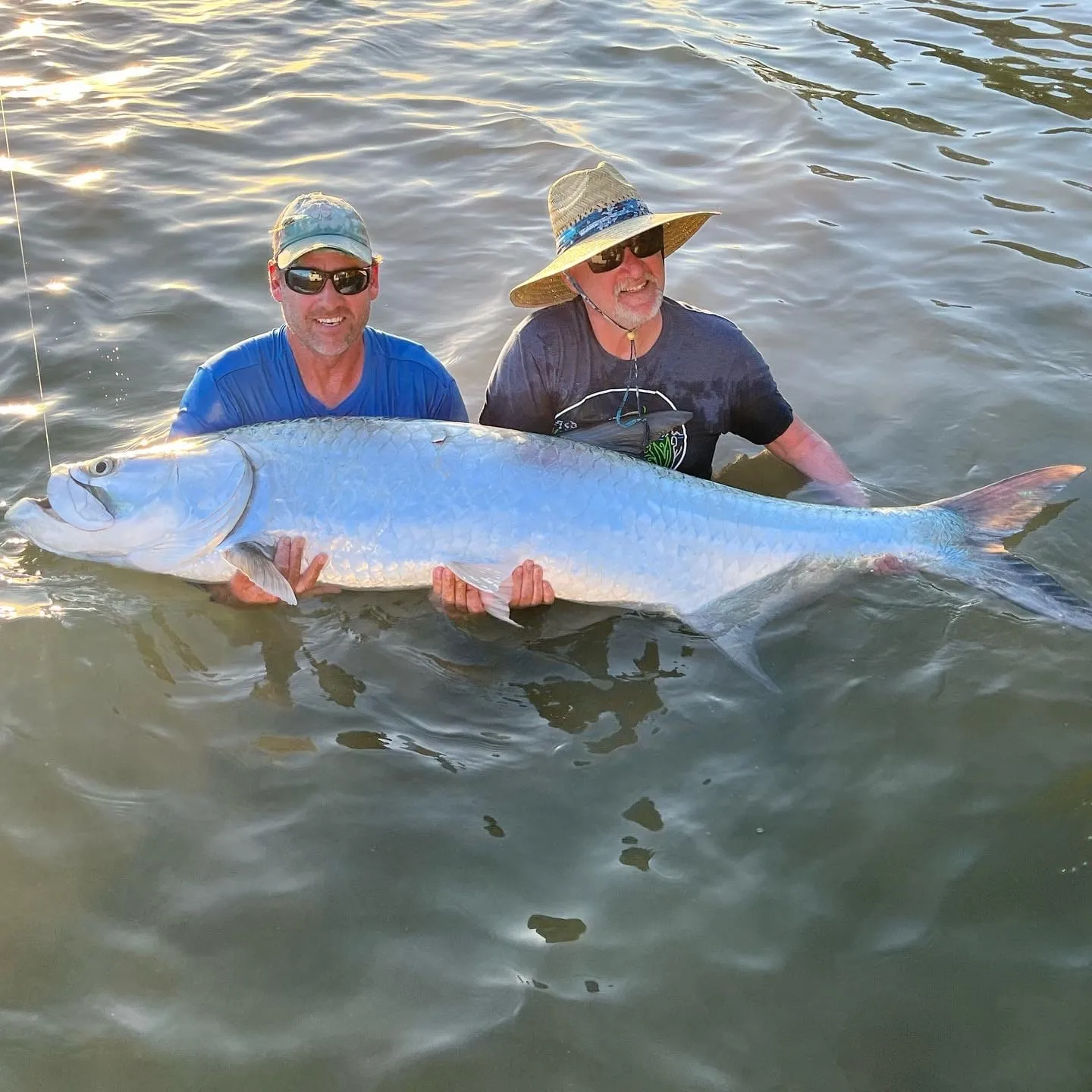 Two anglers in the shallows with a big tarpon before release